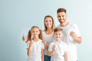 family of four smiling with their toothbrushes