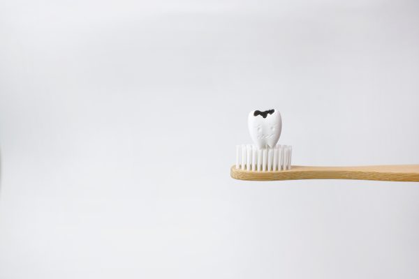 tooth with a cavity sitting on a wooden toothbrush