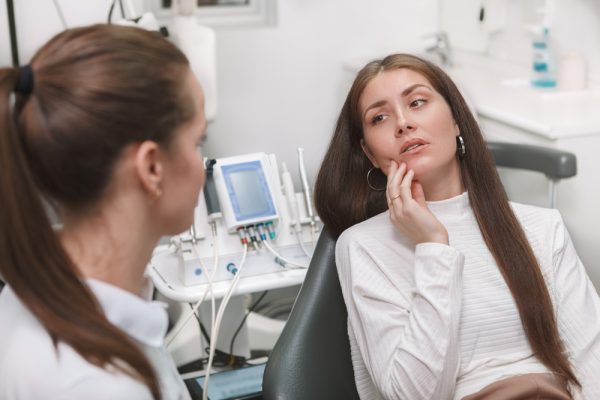 woman sitting in the dental chair explaining to the dentist where it hurts