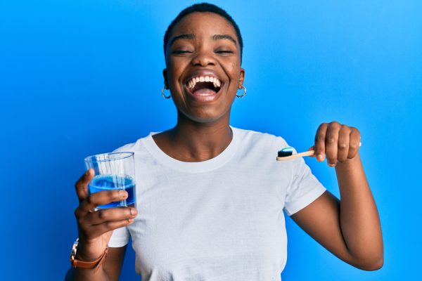 woman holding her toothbrush and mouthwash in her hands