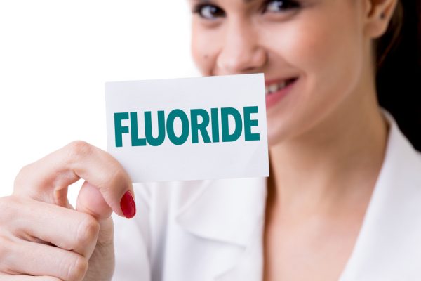 dentist holding up a sign that says "fluoride"