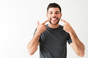 man points at teeth free of tooth decay or gum tissue damage