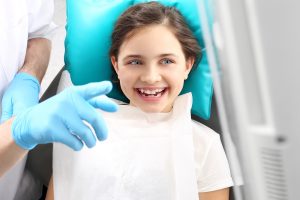 dentist points to screen for child during routine pediatric dental exam