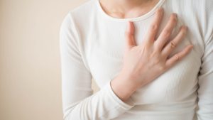 woman places hand over heart while experiencing chest pain